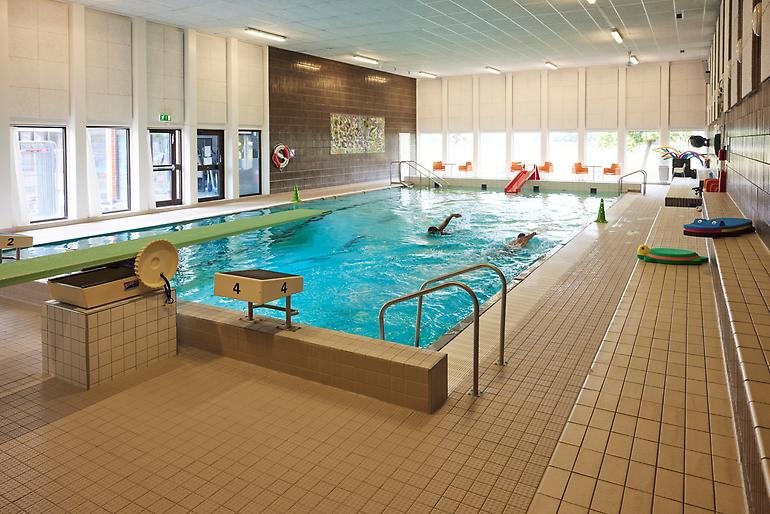 Badbassäng inomhus med två personer som simmar.